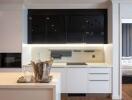 Modern kitchen with white cabinets, black upper cabinets, and integrated appliances adjacent to open bedroom