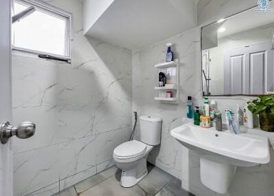 Modern bathroom with white tiles, sink, and toilet