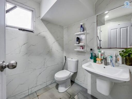 Modern bathroom with white tiles, sink, and toilet