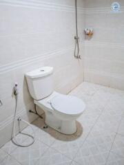 Modern bathroom with white ceramic tile flooring, toilet, and shower