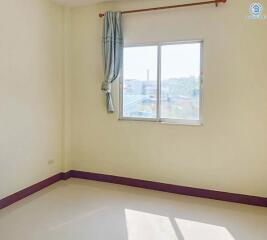 Empty bedroom with window, curtain, and purple baseboards