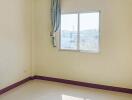 Empty bedroom with window, curtain, and purple baseboards