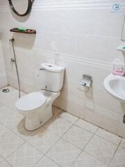 Bathroom with white tiles, toilet, sink, and a wall-mounted shelf