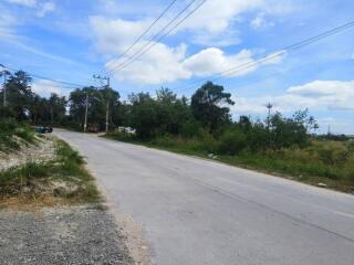 View of a rural road with greenery and a partly cloudy sky