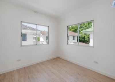 empty bedroom with two windows and wooden floor