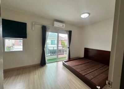 Empty bedroom with wooden flooring, bed frame, and large window