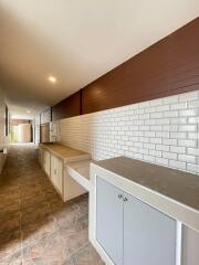 Long hallway kitchen with white tile backsplash and cabinets