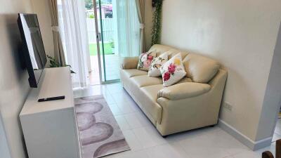 Cozy living room with a cream sofa, wall-mounted TV, and sliding glass doors leading to a patio.