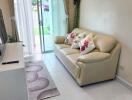 Cozy living room with a cream sofa, wall-mounted TV, and sliding glass doors leading to a patio.