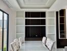 Modern dining room with a white table and cushioned chairs, featuring built-in shelves.