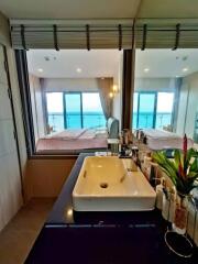 Bathroom with a view of the bedroom and ocean through a large window