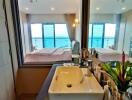 Bathroom with a view of the bedroom and ocean through a large window