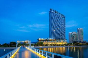 Modern high-rise building by the water with lit pathways