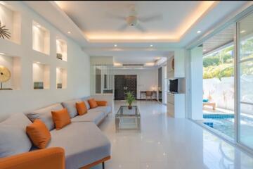 Modern living room with sectional sofa, coffee table, and sliding glass doors opening to a pool area