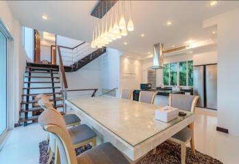 Modern dining area connected to kitchen with contemporary lighting and staircase