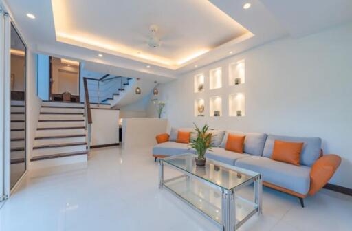 Modern living room with staircase, recessed lighting, and contemporary furniture