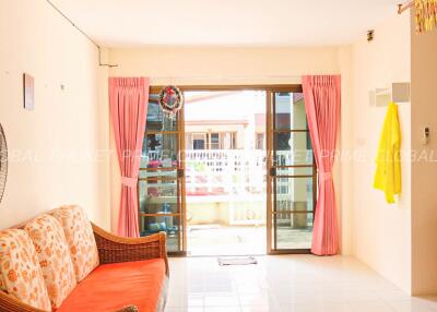 Spacious living room with a wicker sofa, pink curtains, and glass doors leading to a balcony
