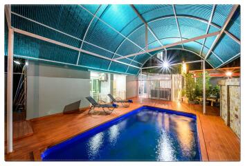 Outdoor swimming pool with sun loungers under a canopy