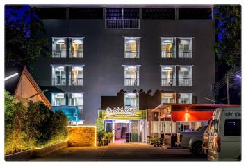 Exterior view of a multi-story residential building with balconies and lights on