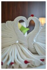 Elegantly folded towel swans on a bed with ambient lighting