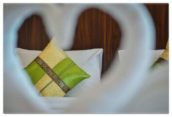 Close-up view of pillows on a bed with a heart-shaped frame in the foreground