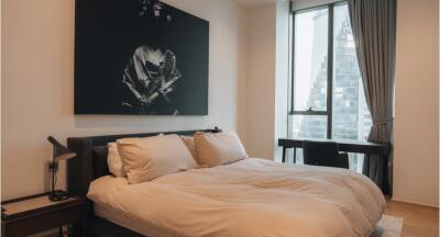 Modern bedroom with large bed, artwork, and city view