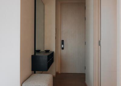 Photo of a hallway with a door, a wall-mounted mirror, a small console table, and a bench