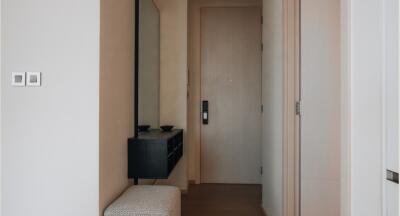 Photo of a hallway with a door, a wall-mounted mirror, a small console table, and a bench