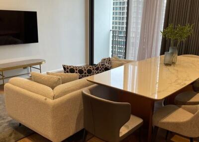 Modern living room with a wall-mounted TV, a large couch, and a dining table with chairs