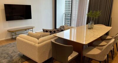 Modern living room with a wall-mounted TV, a large couch, and a dining table with chairs