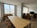 Spacious living room with large windows and wooden dining table