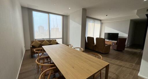 Spacious living room with large windows and wooden dining table