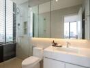 Modern bathroom with glass shower, large mirror, and natural light