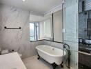 Modern bathroom with marble tiles, glass shower, and standalone bathtub