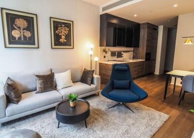 Modern living room with sofa, chairs, and a view of the dining area and kitchen