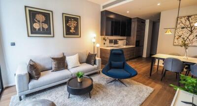 Modern living room with sofa, chairs, and a view of the dining area and kitchen