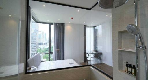 Modern bedroom with glass wall, city view, and ensuite bathroom