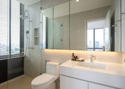 Modern bathroom with a large mirror, glass shower enclosure, and sleek white fixtures