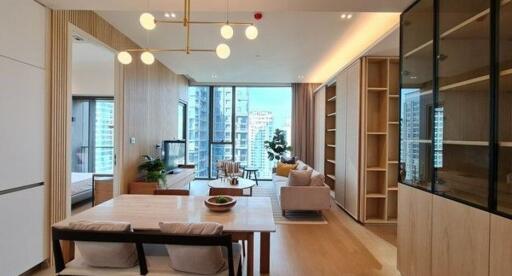 Well-lit modern living area with dining table, seating, and large windows with a city view