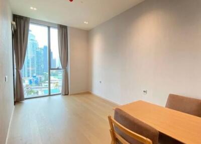 Bright living area with wood flooring, showing a table and chairs near a large window with city views