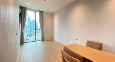 Bright living area with wood flooring, showing a table and chairs near a large window with city views