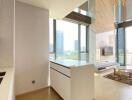 Spacious and bright living area with large windows, modern kitchen area, and city views