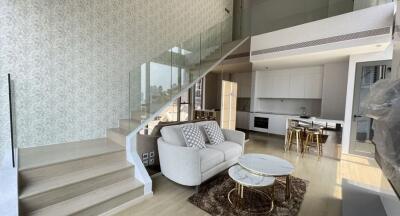 Modern living area with staircase, kitchen, and dining area