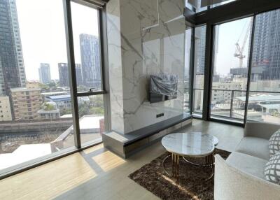 Modern living room with large windows, city view, marble coffee table, and mounted TV