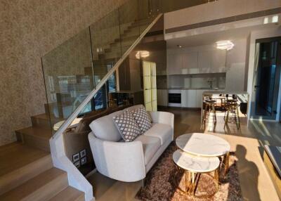 Living room with staircase, modern furniture, and kitchen view