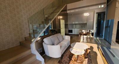 Living room with staircase, modern furniture, and kitchen view