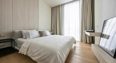 Modern bedroom with a large bed, wooden floor, and a tall window with floor-to-ceiling curtains