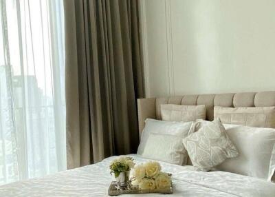 Cozy bedroom with beige tones and tray of flowers on bed