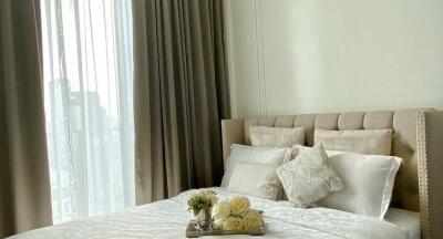 Cozy bedroom with beige tones and tray of flowers on bed