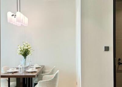 Modern dining area with a wooden table and upholstered chairs, decorated with a flower vase and set for meal